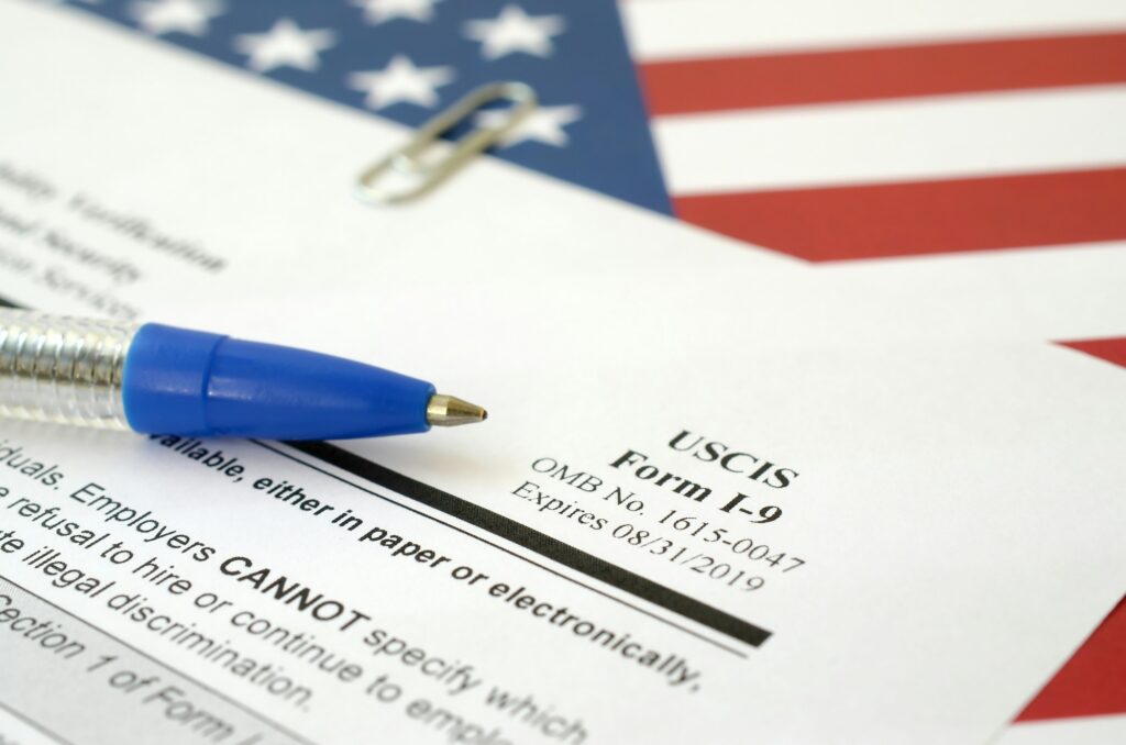 I-9 Employment Eligibility Verification blank form lies on United States flag